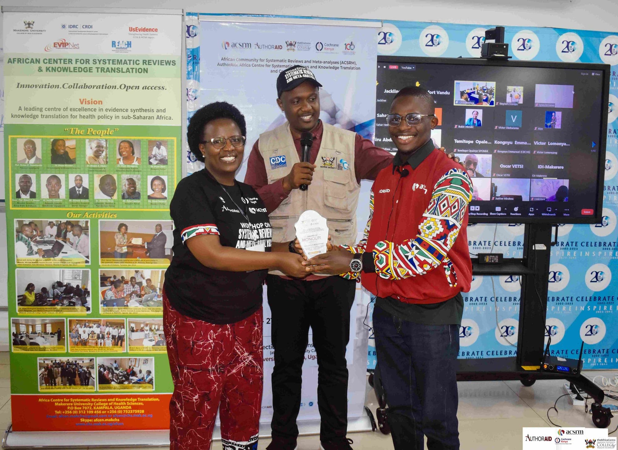 SRN team members receiving an Award of Honour at a hybrid workshop, with online participants visible on the screen behind.
